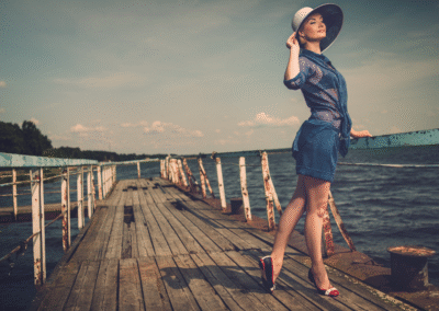 Femme élégante en chapeau blanc debout sur la vieille jetée en bois