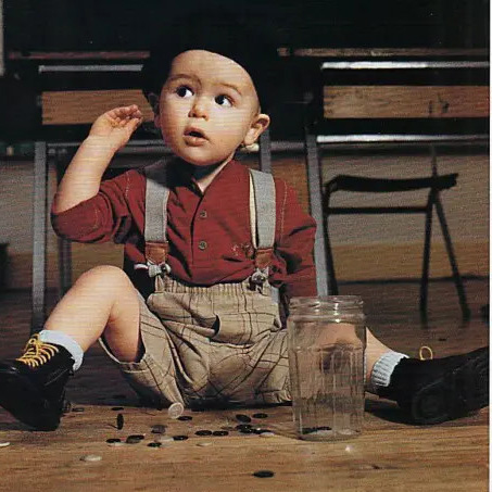 Jeune enfant assis avec des vêtements colorés et un chapeau noir