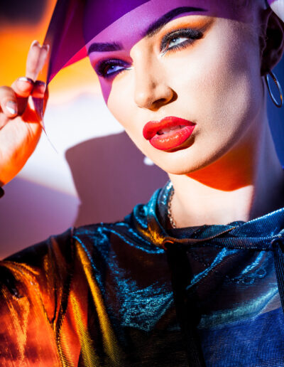 concept de mode - portrait d'une belle femme en veste à capuche et lunettes de soleil sous une lumière vive mixte